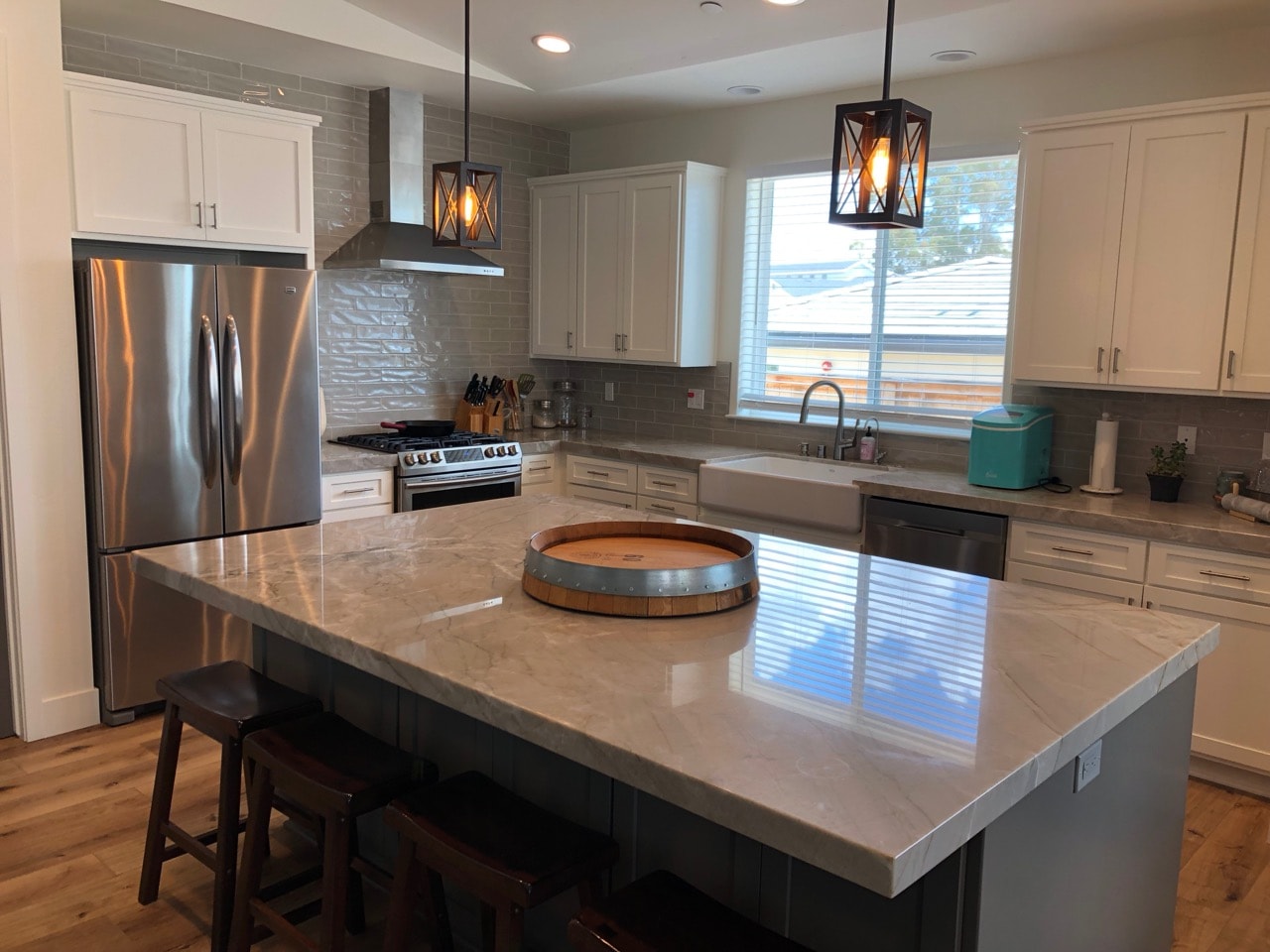 Kitchen remodel with quartz island, white cabinetry, and pendant lighting by Capps Construction