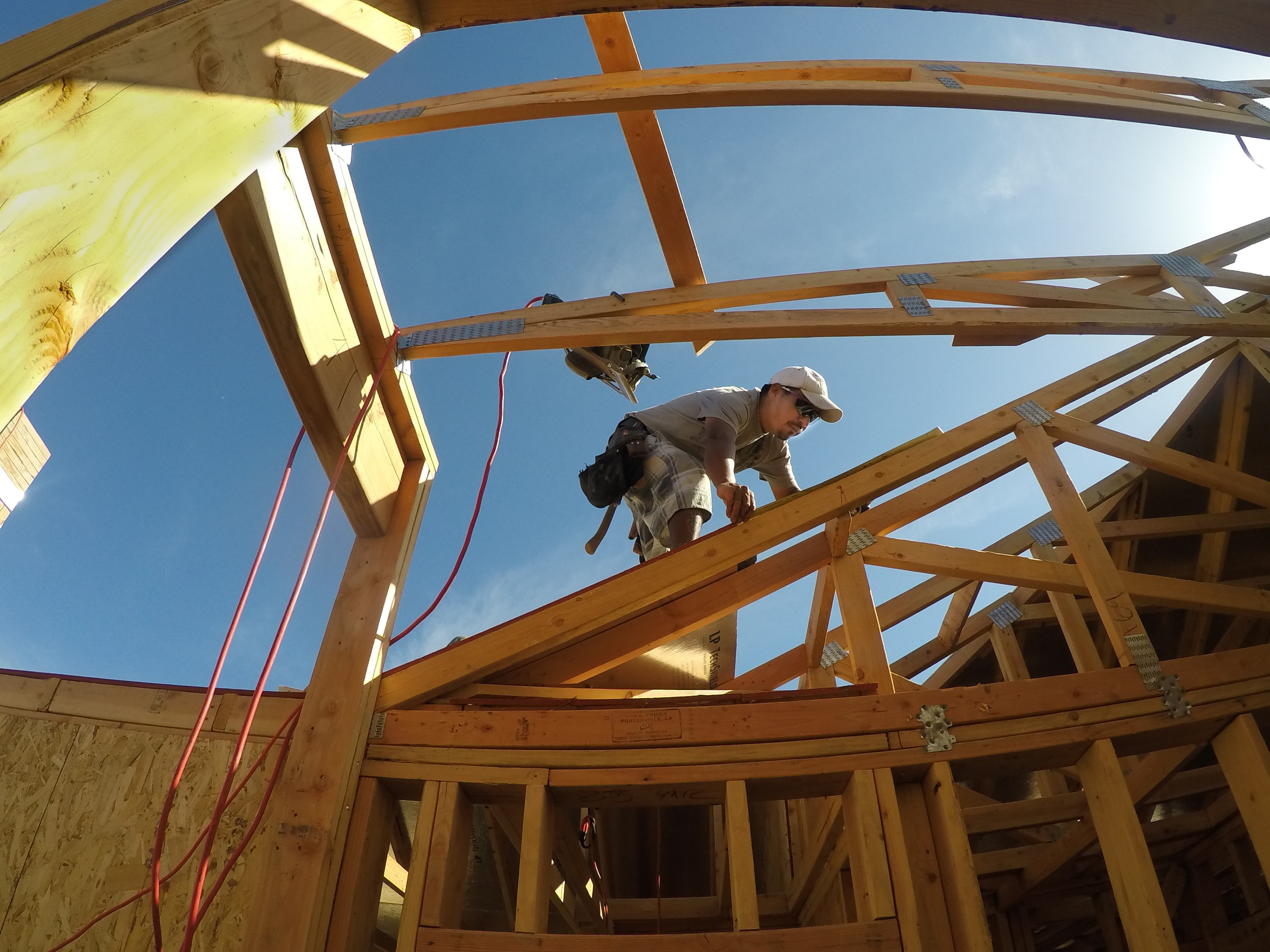 Roof framing construction with worker on curved trusses by Capps Construction