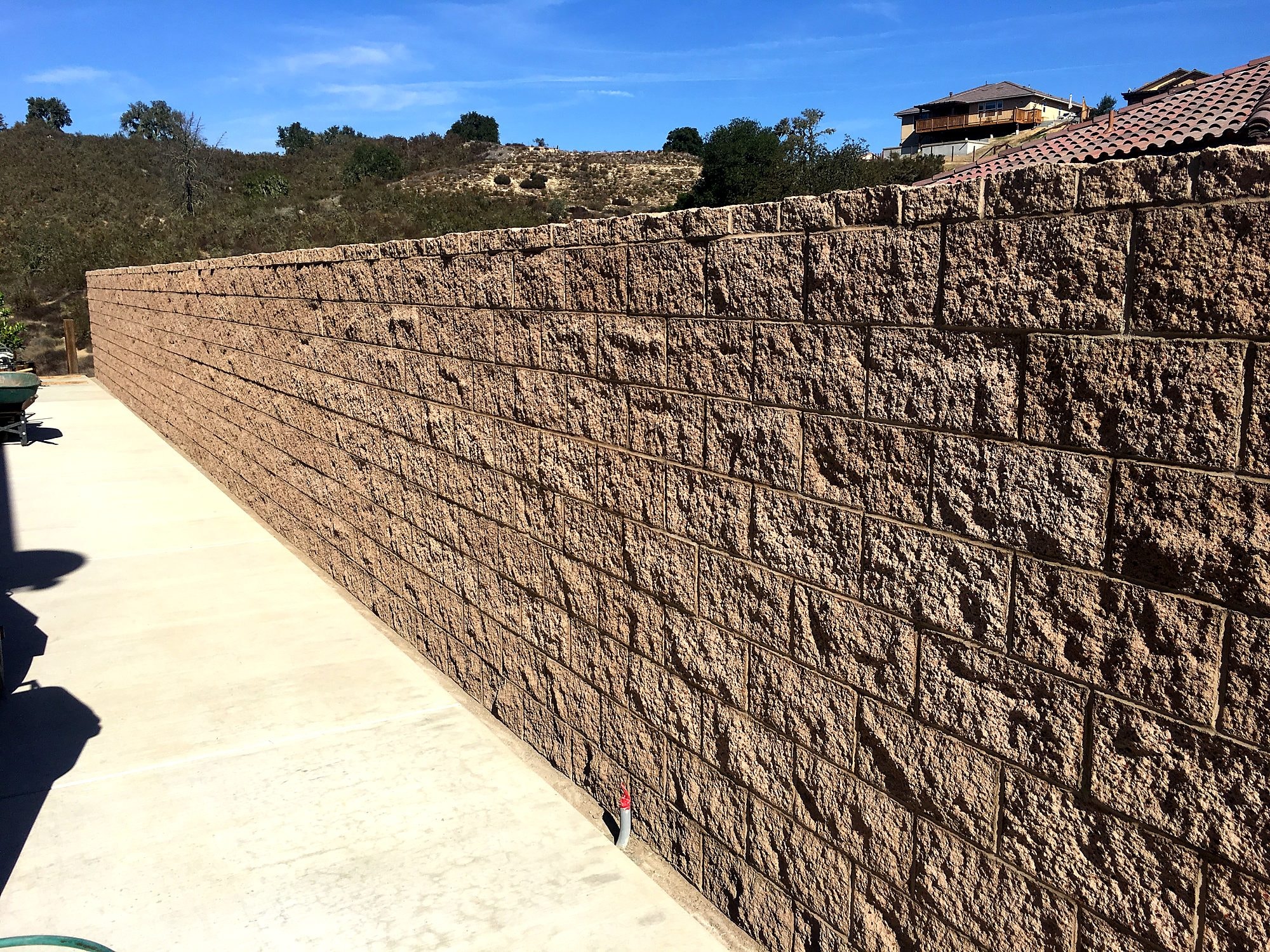 Split-face block retaining wall along a concrete walkway by Capps Construction