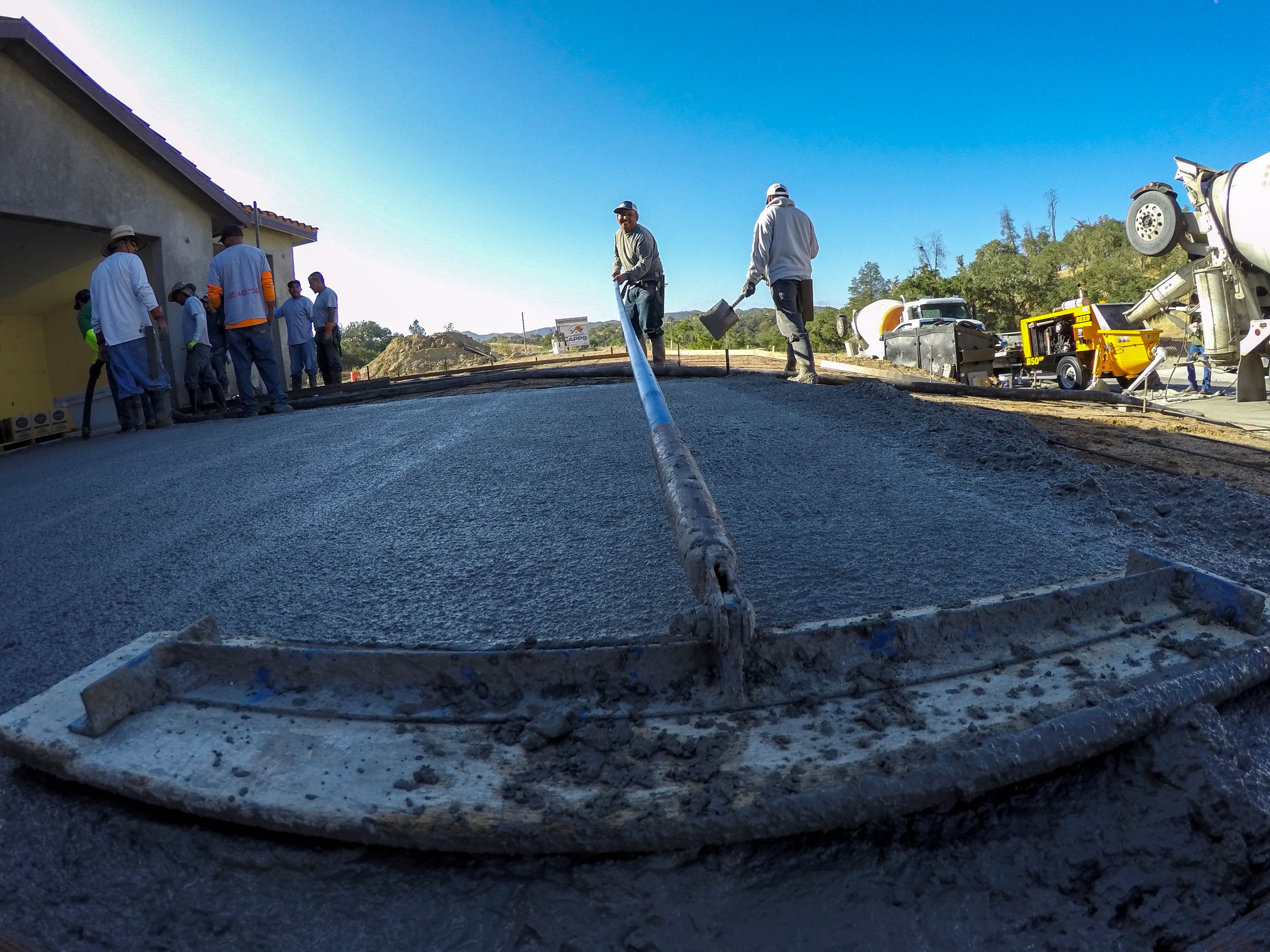 Crew screeding a freshly poured concrete driveway slab