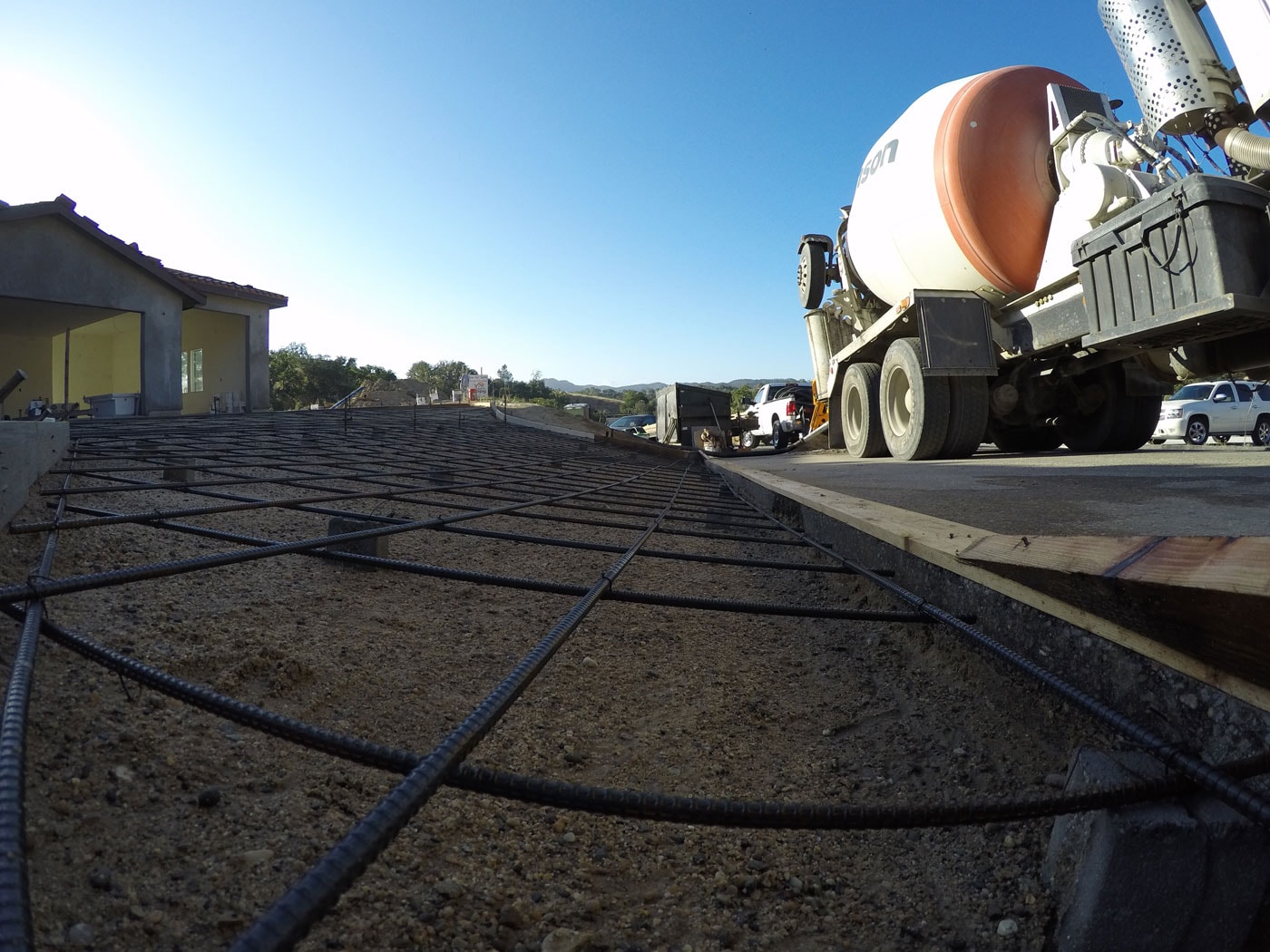 Rebar grid tied over compacted base for a concrete driveway pour, with the mixer truck on site